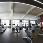 Ranking klubów fitness w Gdyni – wnętrze nowoczesnej siłowni z ćwiczącymi osobami