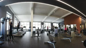 Ranking klubów fitness w Gdyni – wnętrze nowoczesnej siłowni z ćwiczącymi osobami
